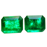 Two emerald green gemstones on a white background