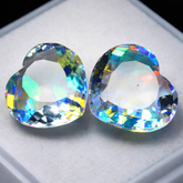 Two multicolored gemstones on a white surface