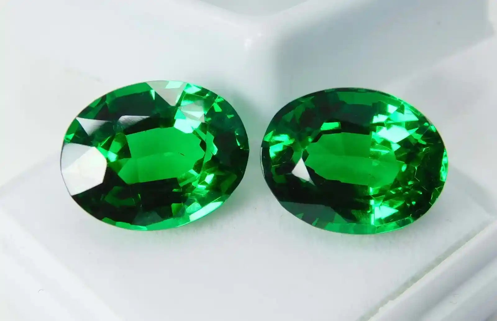 Two green gemstones on a white background