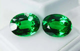 Two green gemstones on a white background