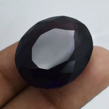 Faceted black gemstone held between fingers against a white background