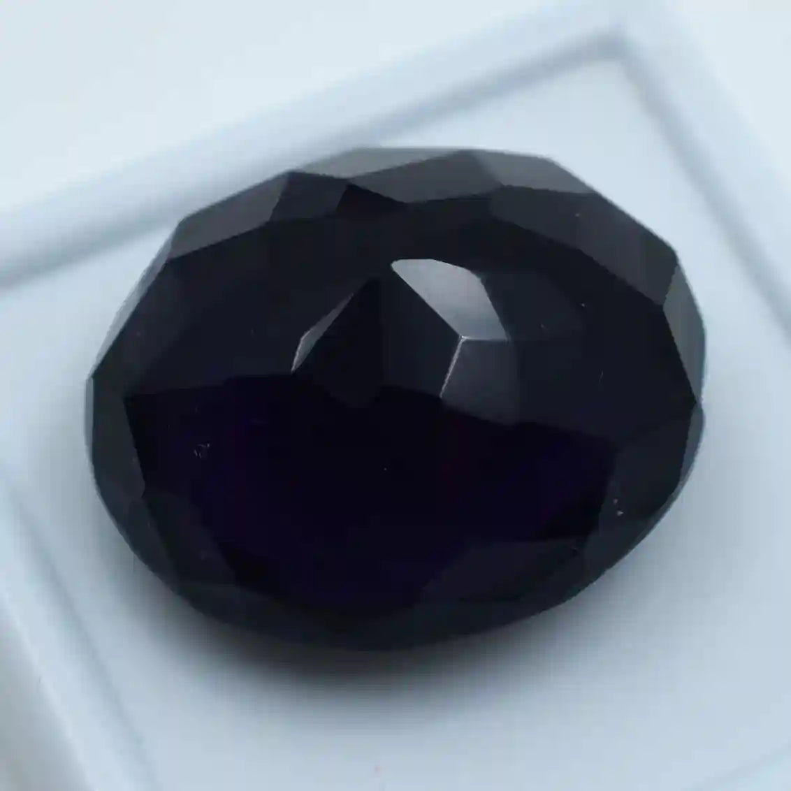 Faceted black gemstone on a white background
