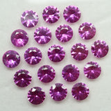 Natural round-cut pink rubies neatly arranged on a plain surface – 12 certified gemstones from Mozambique