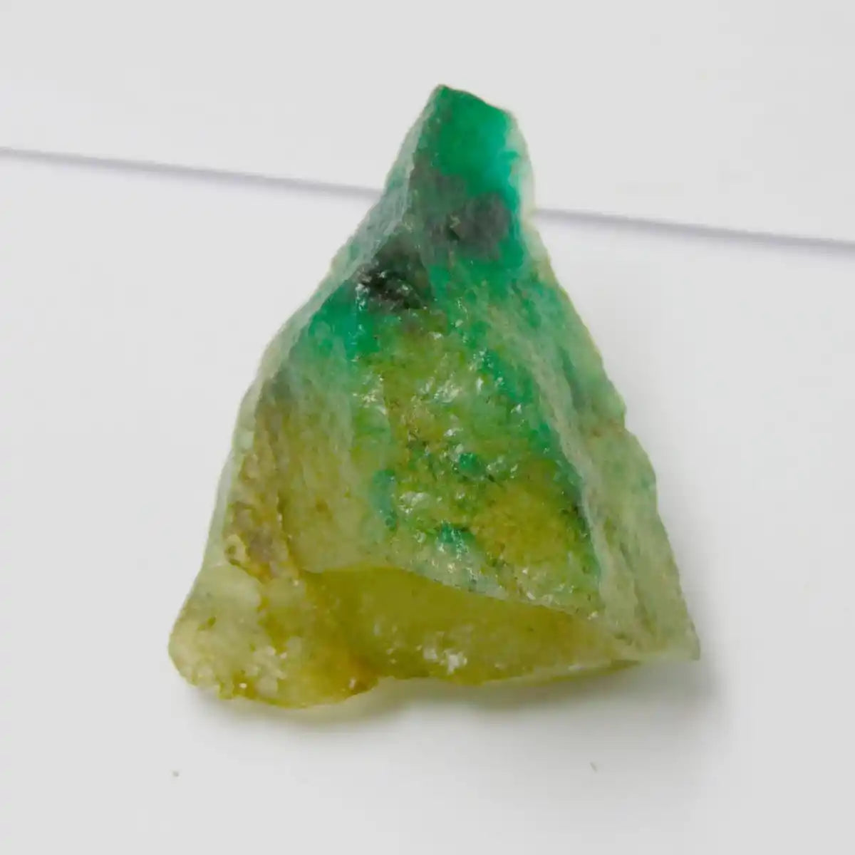 Triangular crystal with green and yellow colors on a white background