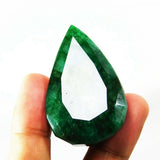 Natural Muzo Colombian emerald held upright between fingers, showcasing its vivid green hue and oversized pear shape.