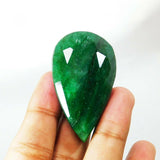 Emerald gemstone facing downward held in hand