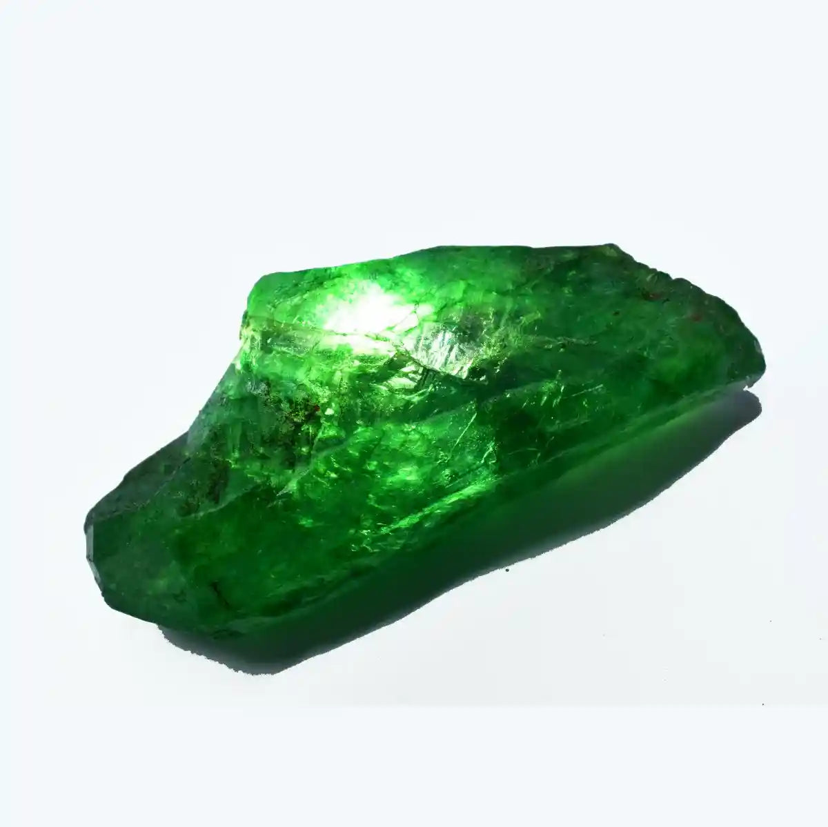 Raw emerald crystal on a white background
