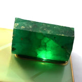 Green crystal on a reflective surface with a white background