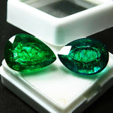 Certified 18.52 Ct pear-cut emeralds placed in a white gel container, shown in soft shadowed lighting to bring out their medium-to-dark green tones and eye-clean clarity
