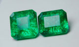 Brightened display of two natural green square emeralds with excellent cut, showing their clarity-enhanced transparency and elegant proportions on a white surface.

