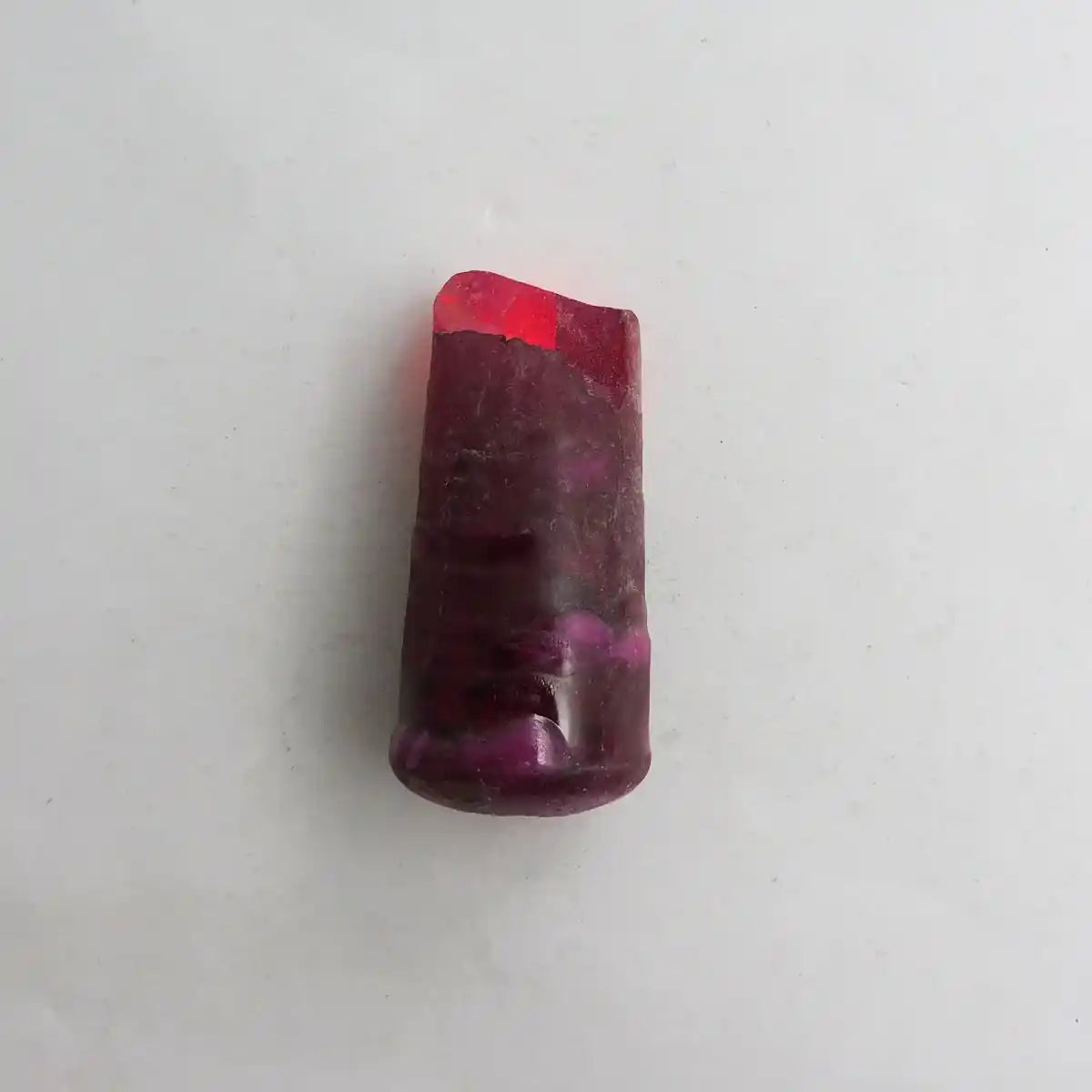 Polished red-purple gemstone on a white background