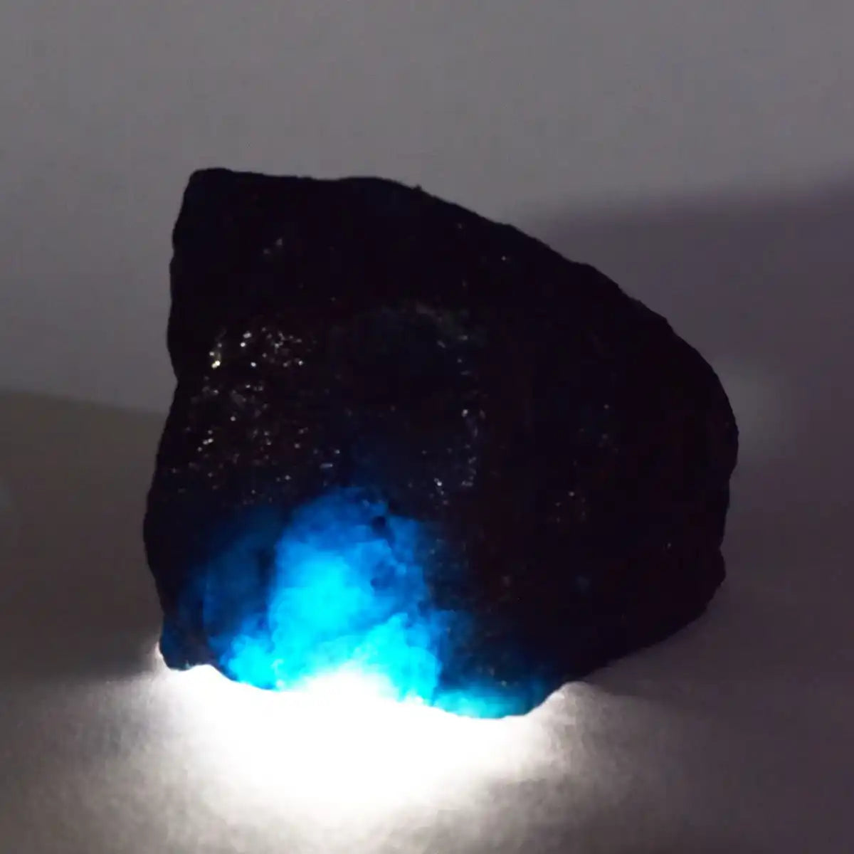 Black rock with a glowing blue interior on a white background