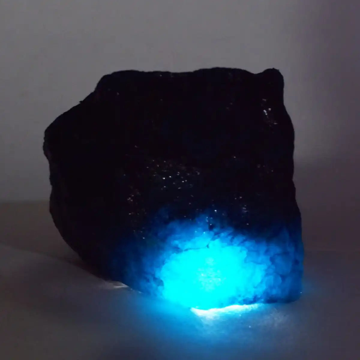 Rock-like object with a glowing blue interior on a plain background