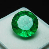 8.23 carat round cut Colombian emerald placed inside a white square case with a black background, highlighting the gem's vivid green color and precision cut.