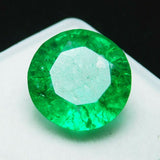Highly reflective 8.23 carat round Colombian emerald glowing with bright green brilliance under intense lighting.