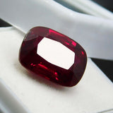 Close-up of 10.10 Ct cushion cut red ruby resting on white box – certified natural gemstone from Mozambique