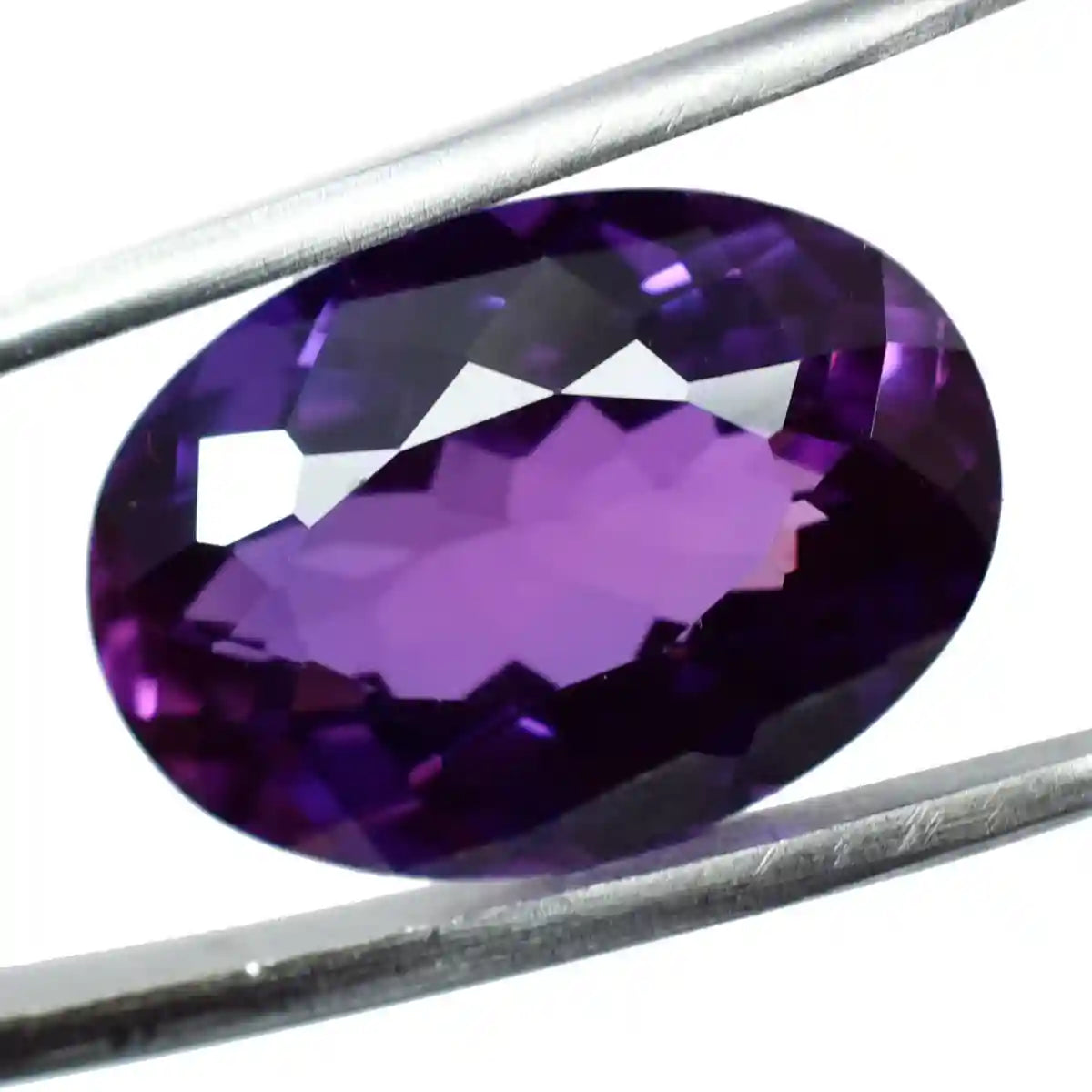 Purple gemstone held between two metal prongs on a white background