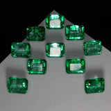 Top view of 10 certified loose emerald gemstones with translucent green shine