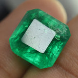 Zoomed-in image of 9.65 Ct Natural Emerald stone held between fingers, highlighting vibrant green color and excellent emerald cut