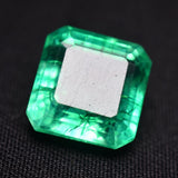 Emerald cut natural green gemstone placed on a solid black background, highlighting its translucency and excellent cut