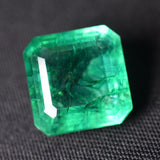 Translucent emerald cut gemstone with eye-clean clarity on grey background, showcasing crystal-clear structure and symmetry