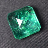 Backside view of 7.88 carat natural emerald stone showing base finish and cut quality against neutral backdrop

