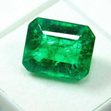 Certified green emerald gemstone reflecting light on smooth clear surface, showcasing clarity and luster