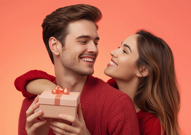 Man and woman exchanging a gift with a pink box and red ribbon on an orange background