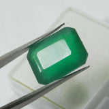 Green gemstone held between tweezers on a white background