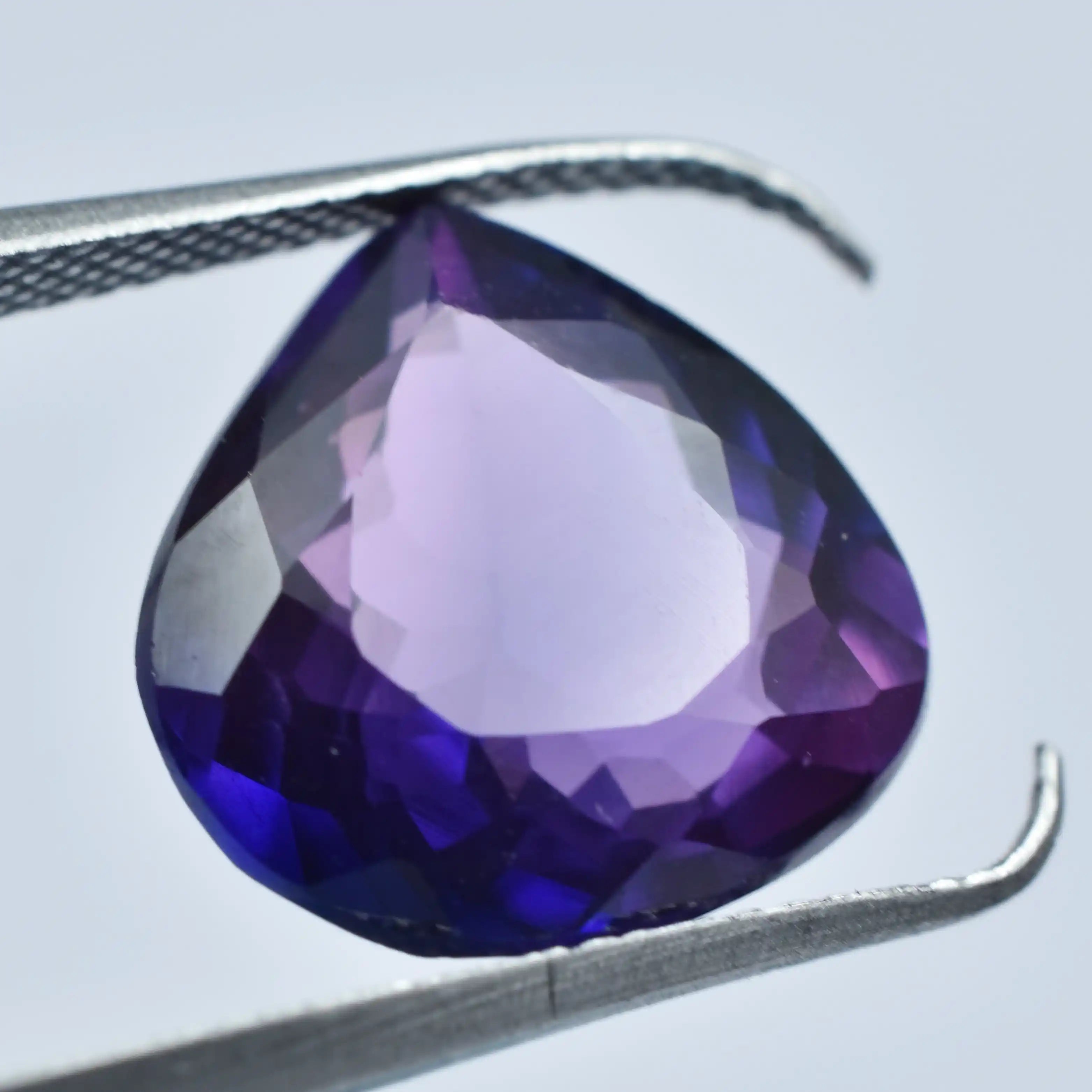 Vivid purple amethyst gemstone, finely faceted, triangle shape, smooth reflective finish.