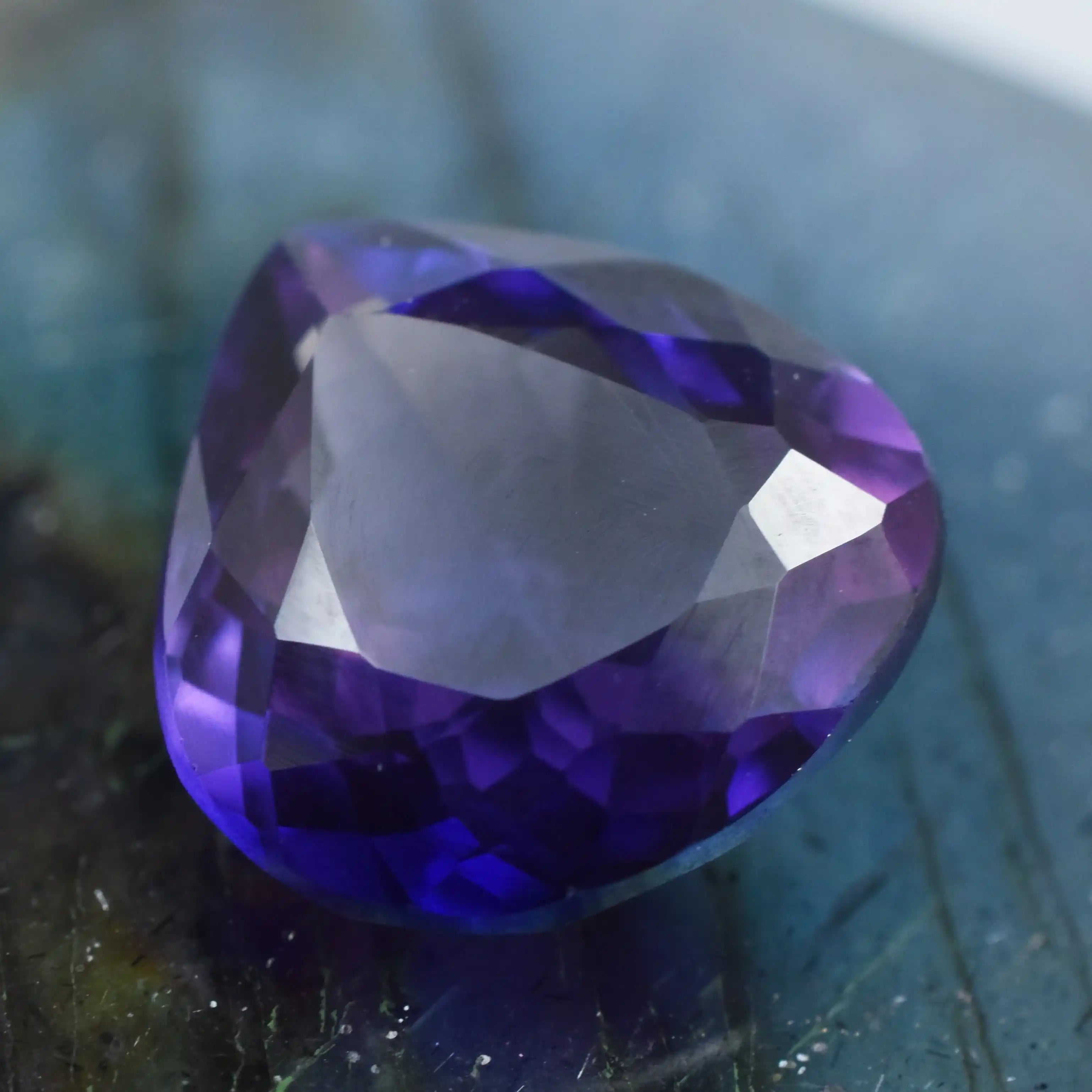 Natural violet-purple gemstone in trillion cut, polished surface with rich color saturation.