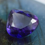 Natural violet-purple gemstone in trillion cut, polished surface with rich color saturation.