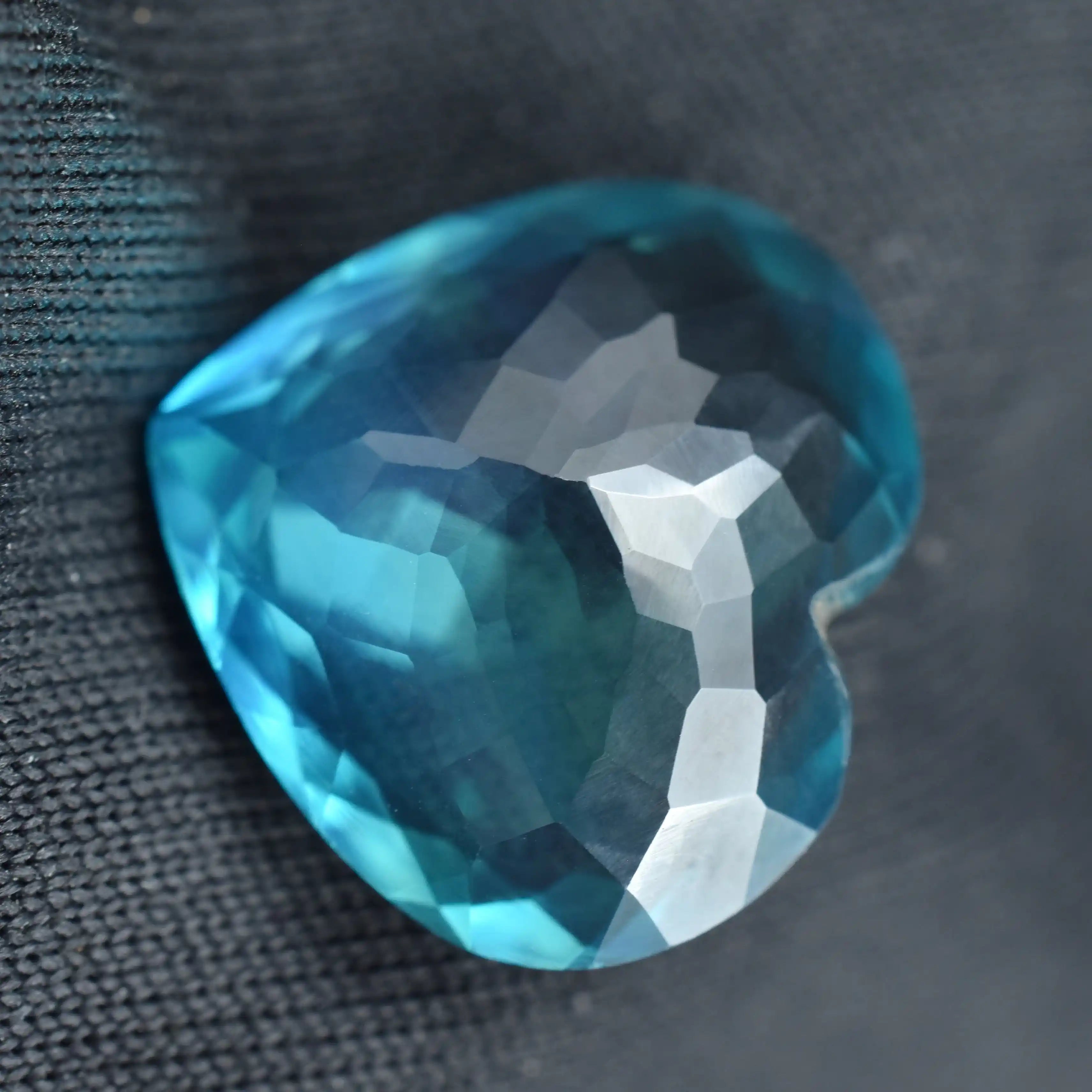 Faceted blue gemstone on a textured black background