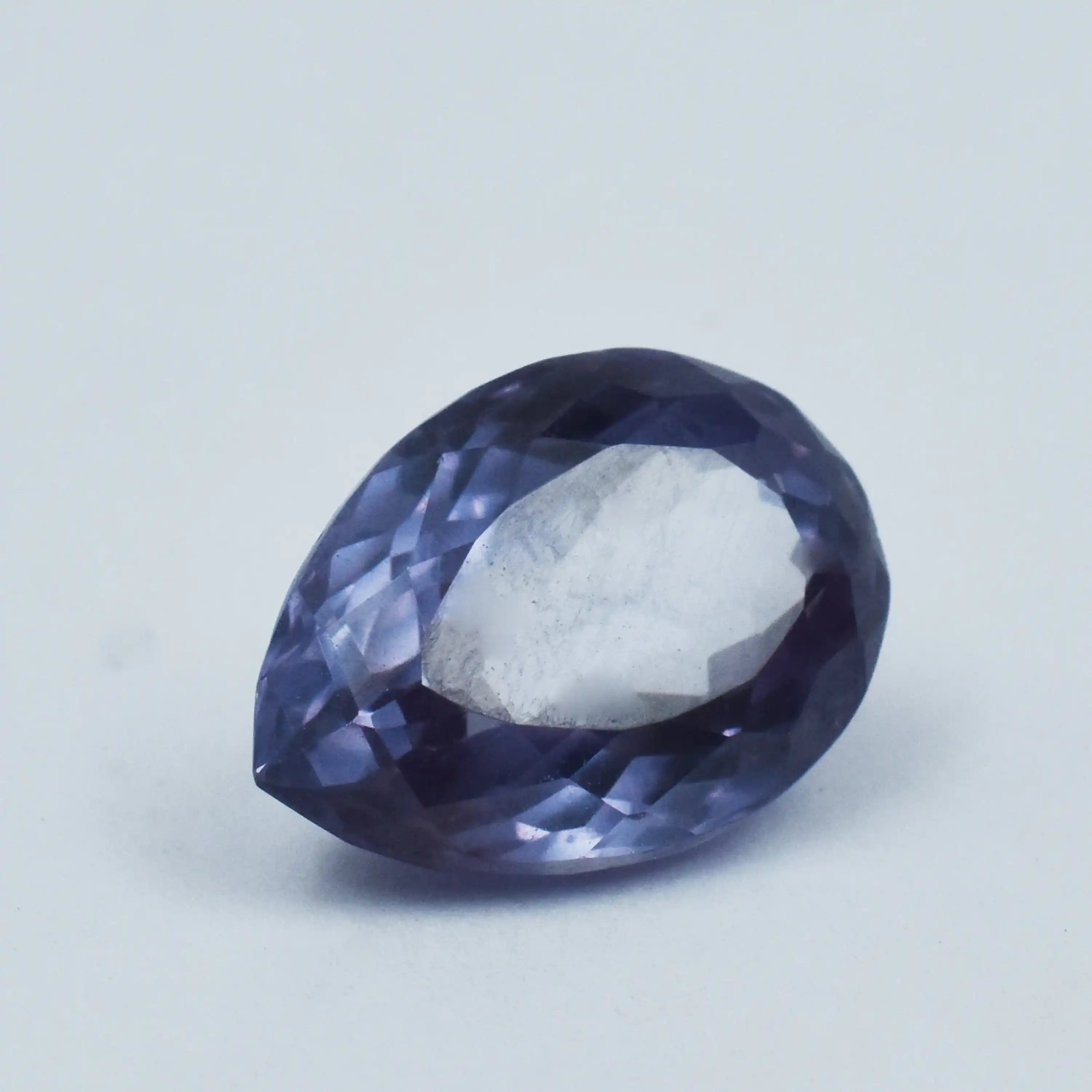 Faceted purple gemstone on a light gray background