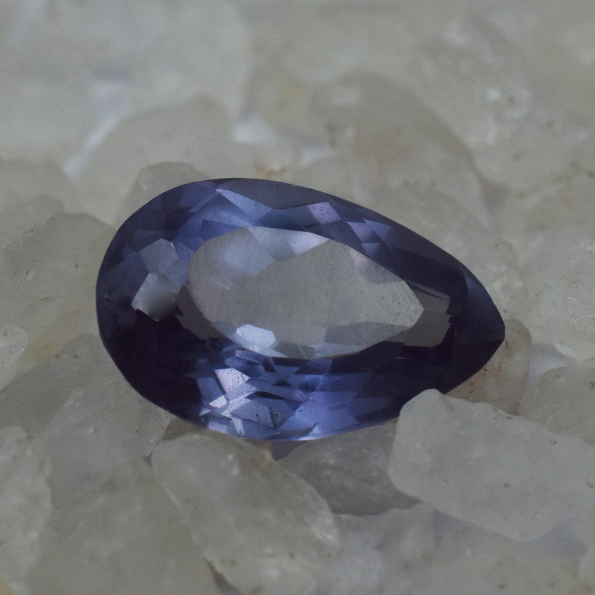 Natural Alexandrite centered among white rough stones showcasing color-change effect