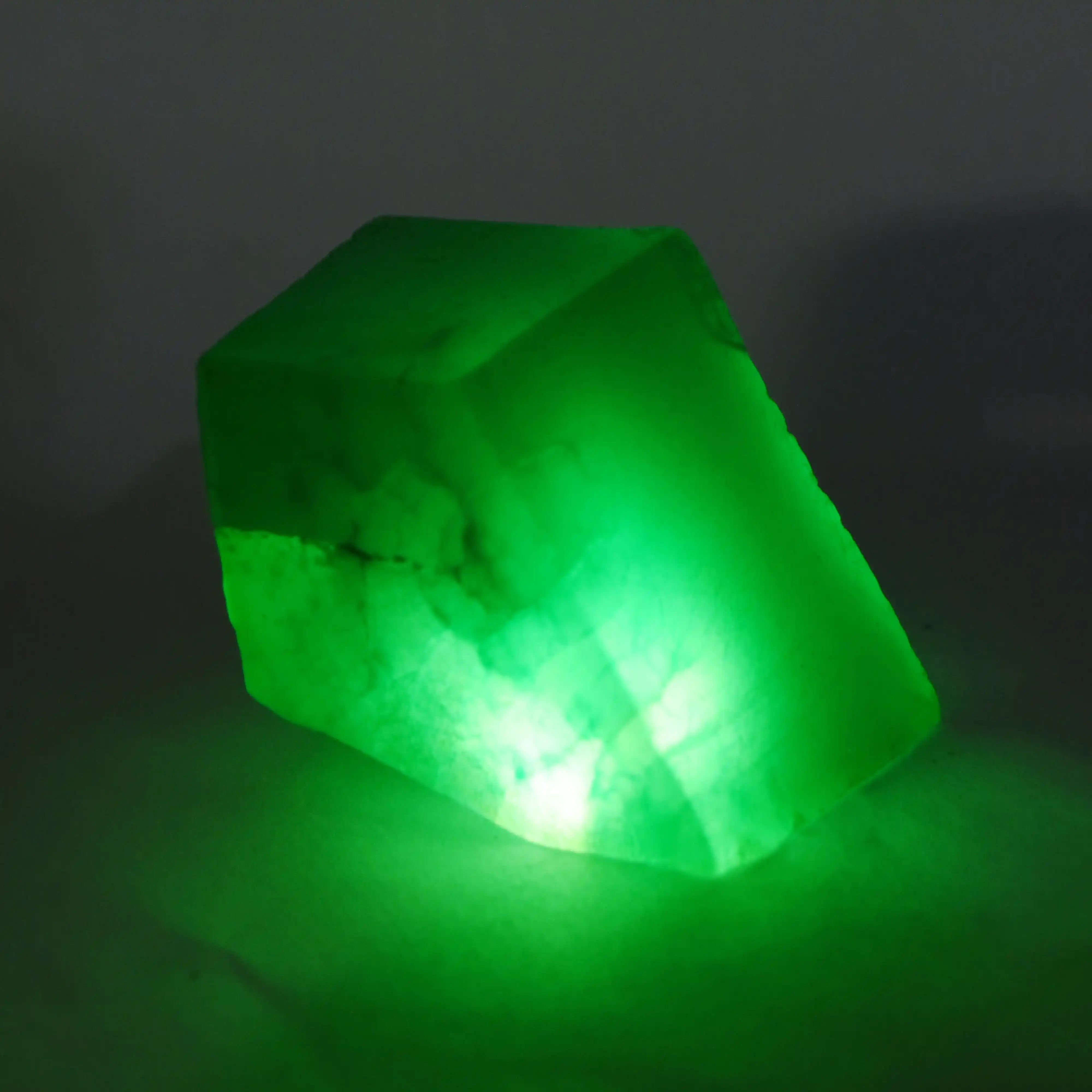 Polished emerald-green jade gemstone raw crystal cut into rectangular shape.