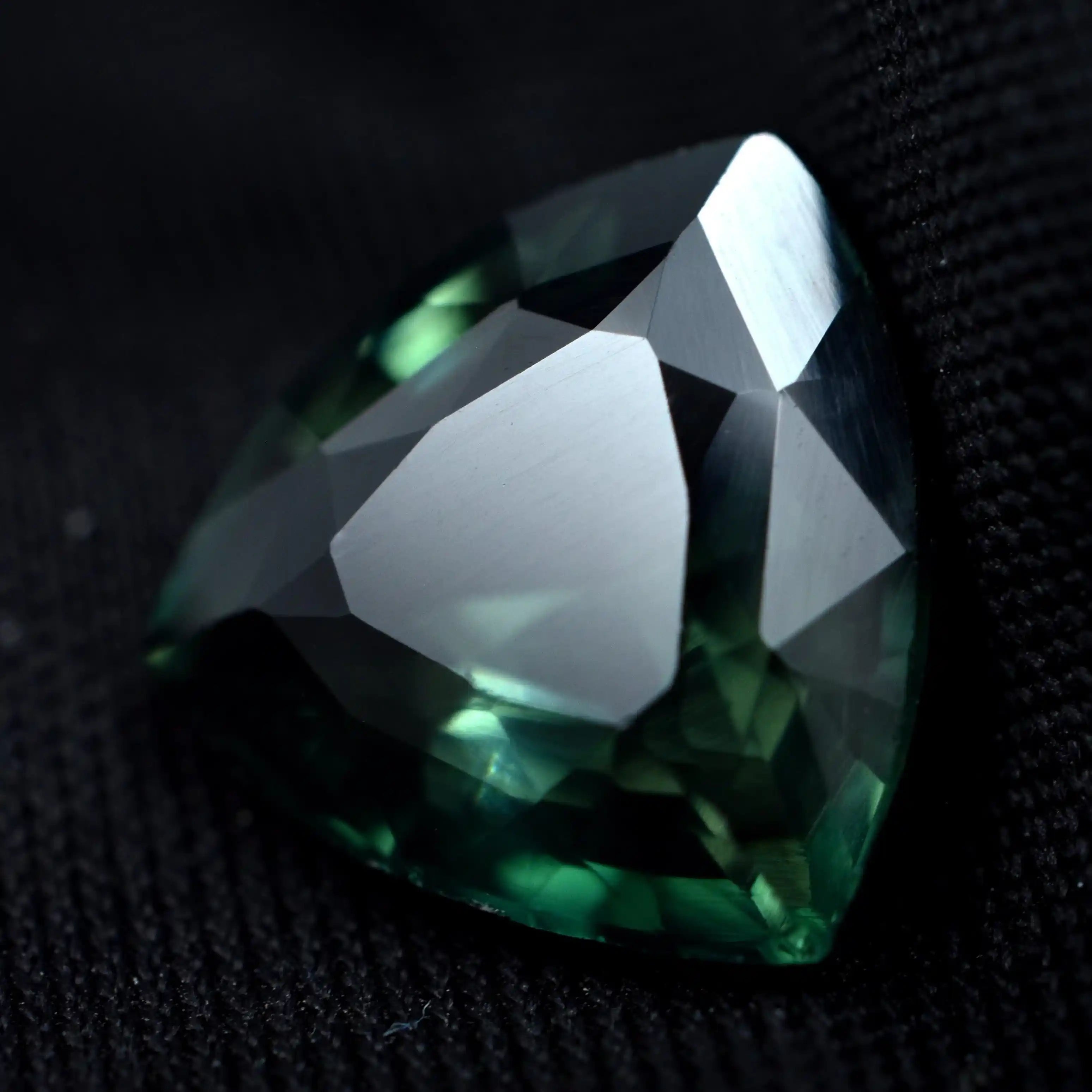 Faceted green gemstone on a textured black background