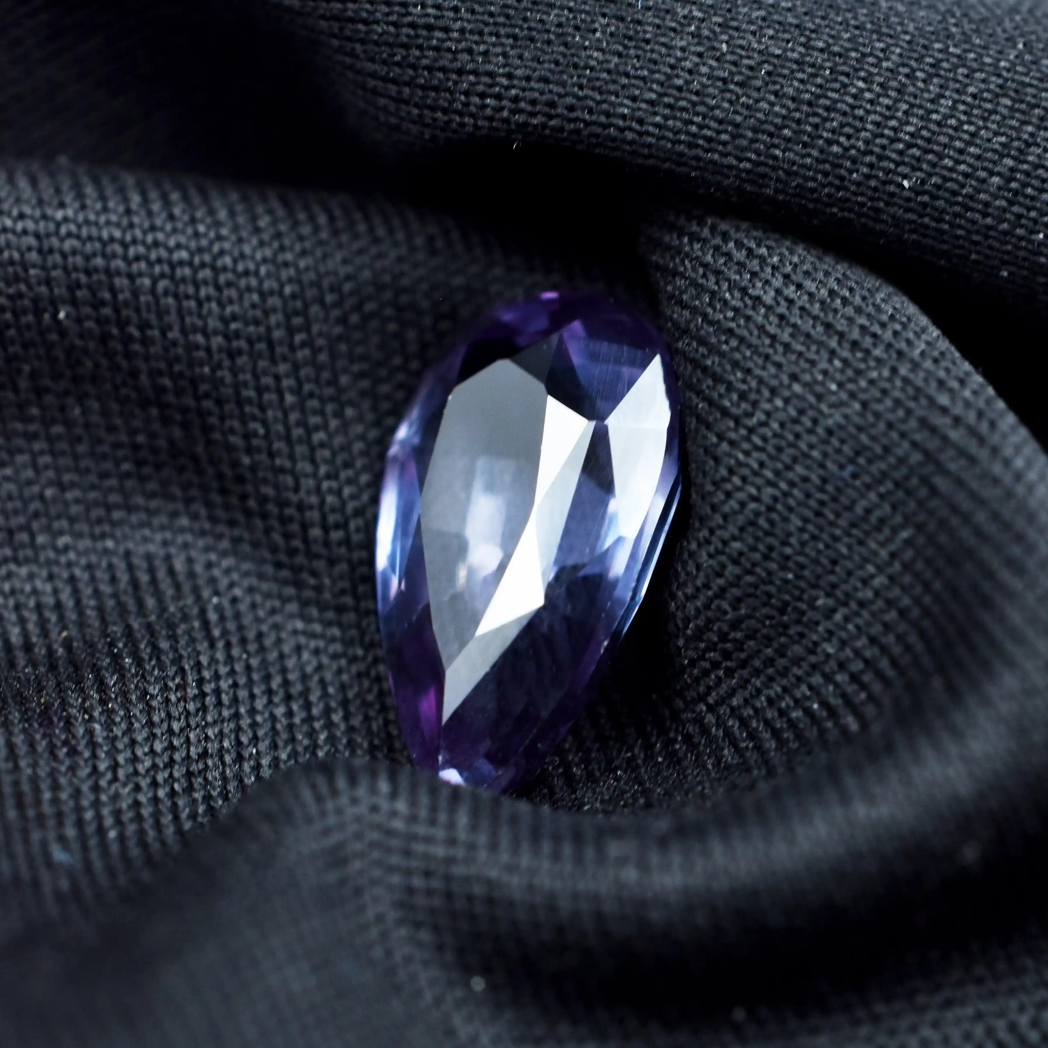 Faceted purple gemstone on black fabric