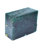 “Uncut green mineral stone with natural texture resting on raw purple gemstones.”