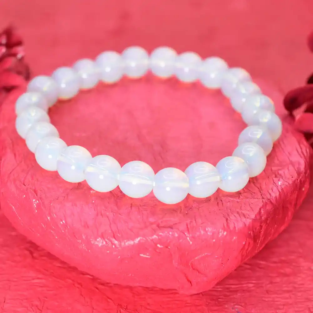 White beaded bracelet on a textured pink surface