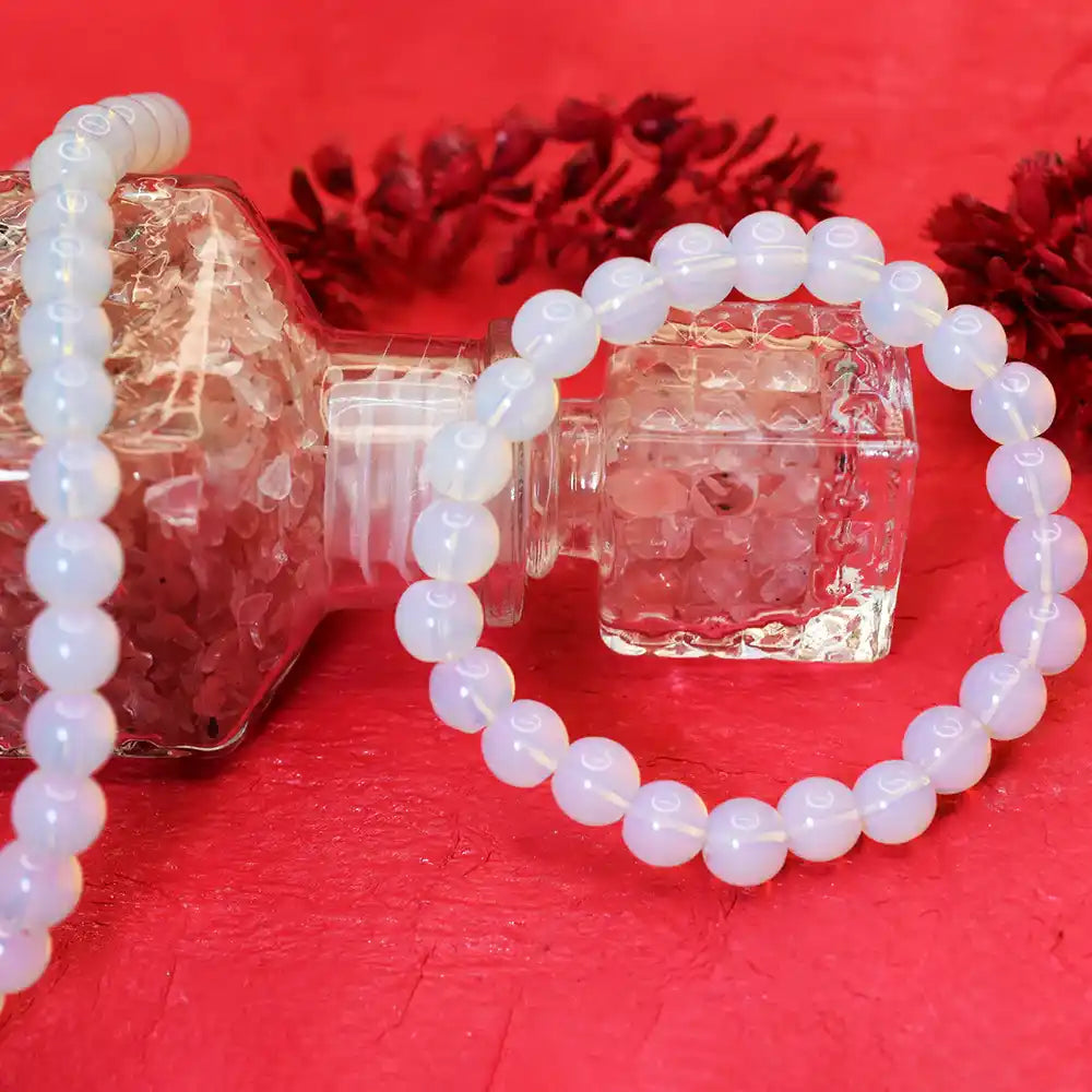 White beaded bracelet on a clear bottle with a red background