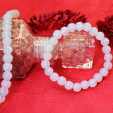 White beaded bracelet on a clear bottle with a red background