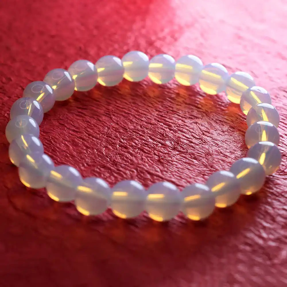 White beaded bracelet on a red textured surface