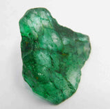“Uncut emerald-like crystal showing rough surfaces and deep green color tones.”