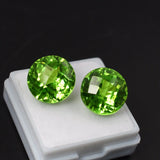 Two green gemstones on a white stand against a black background