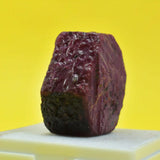 Purple rock on a white surface with a yellow background