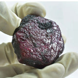 Mineral sample held by a gloved hand on a white background