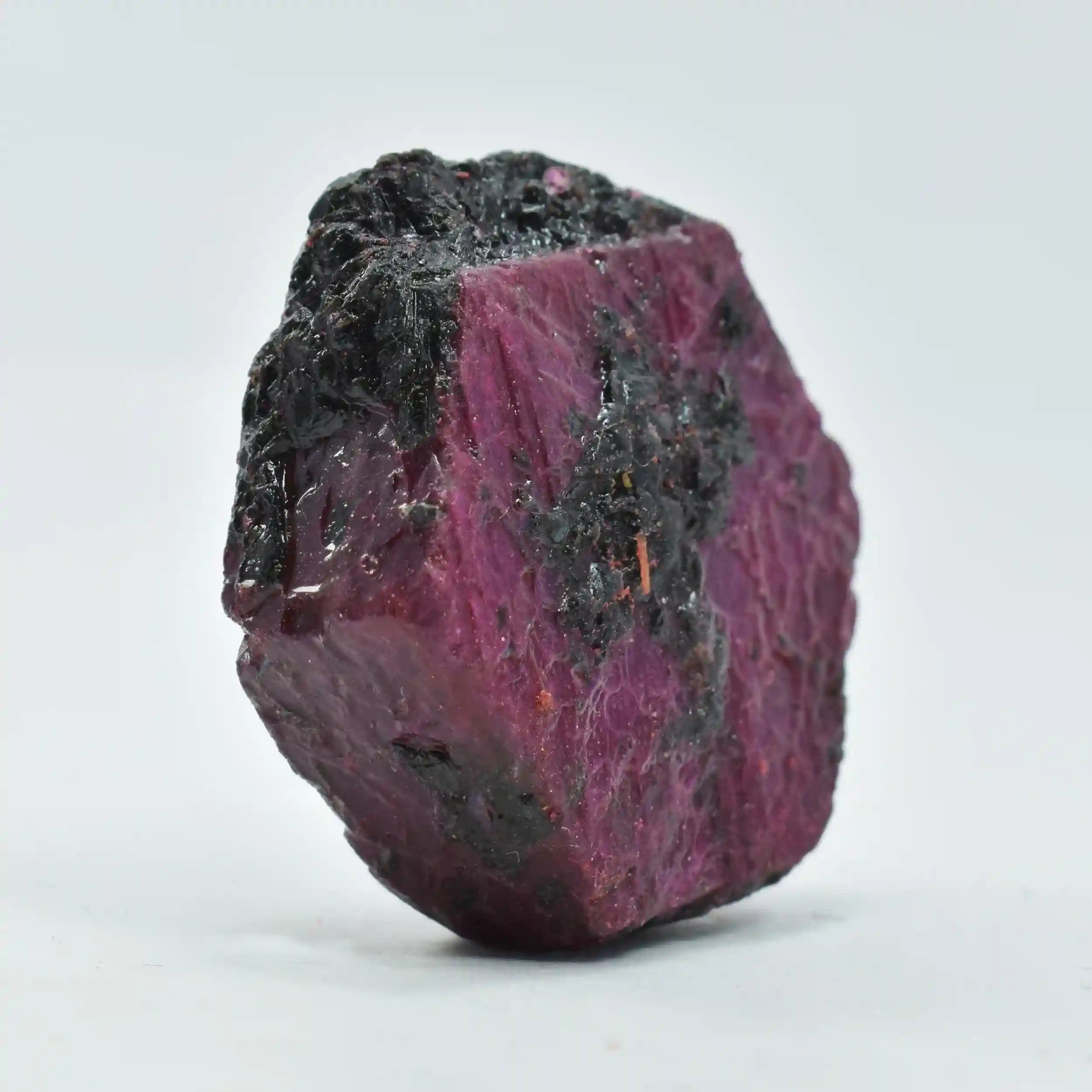 Raw ruby crystal on a light gray background