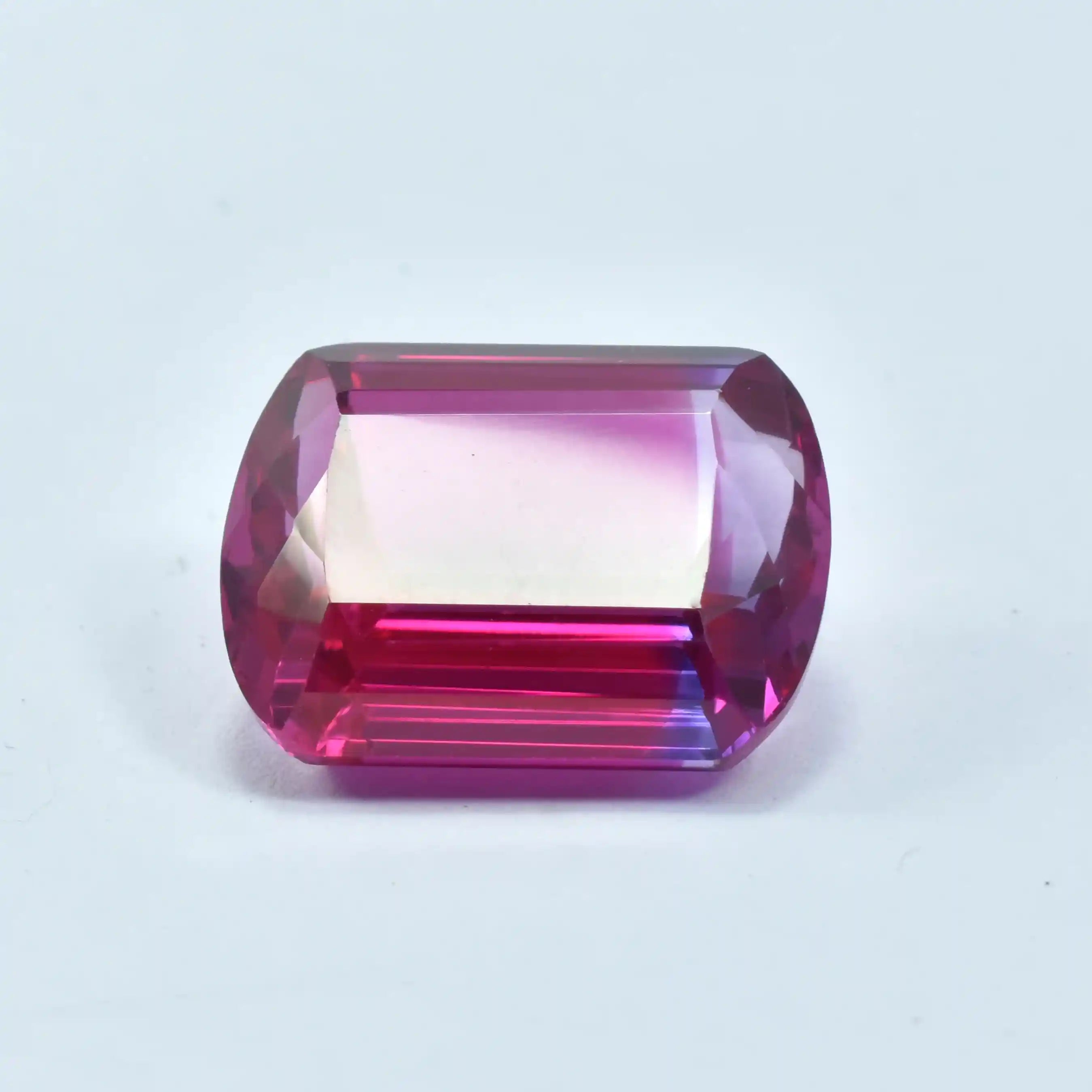 Faceted gemstone with pink and purple hues on a white background