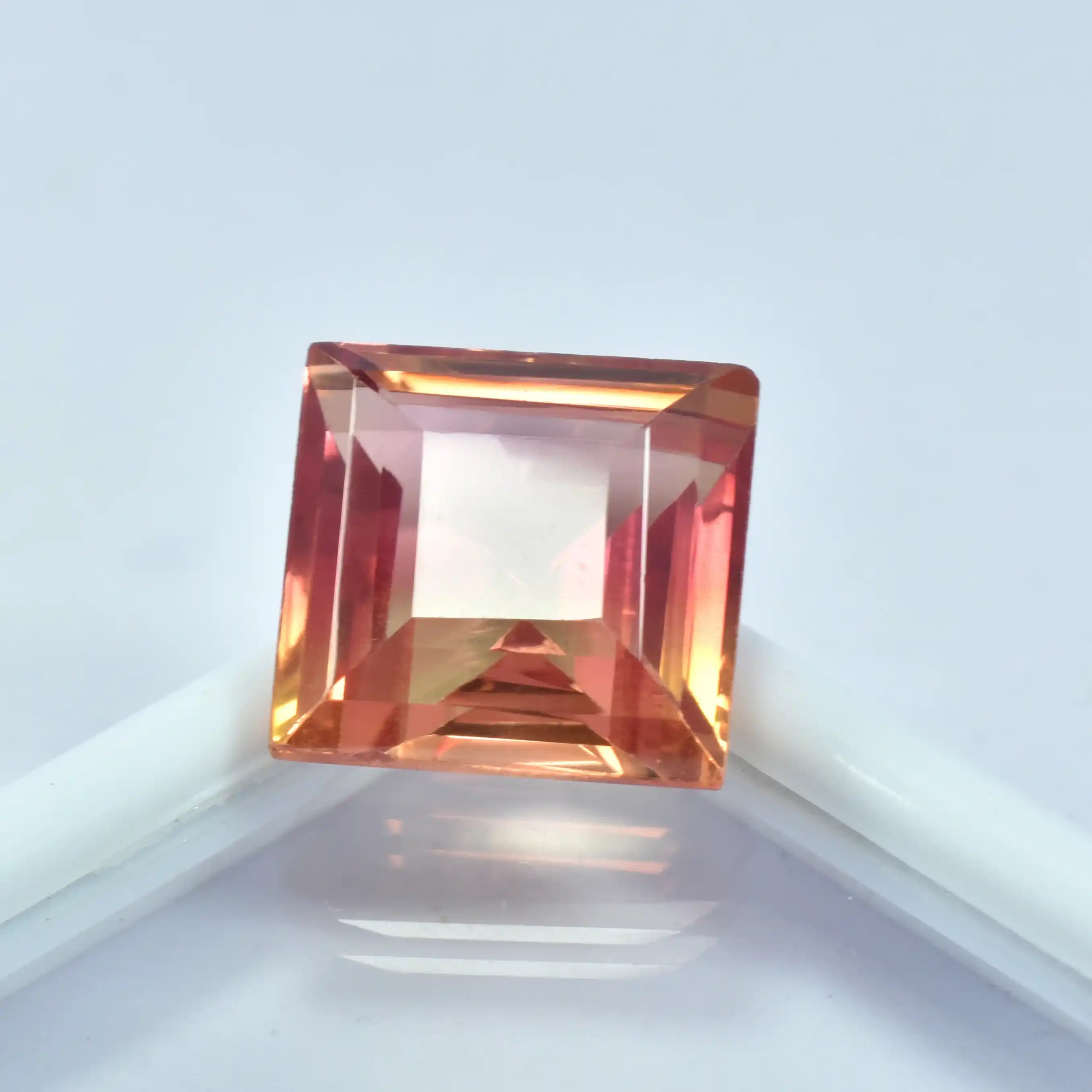 Square-cut gemstone with a multicolor gradient on a light gray background